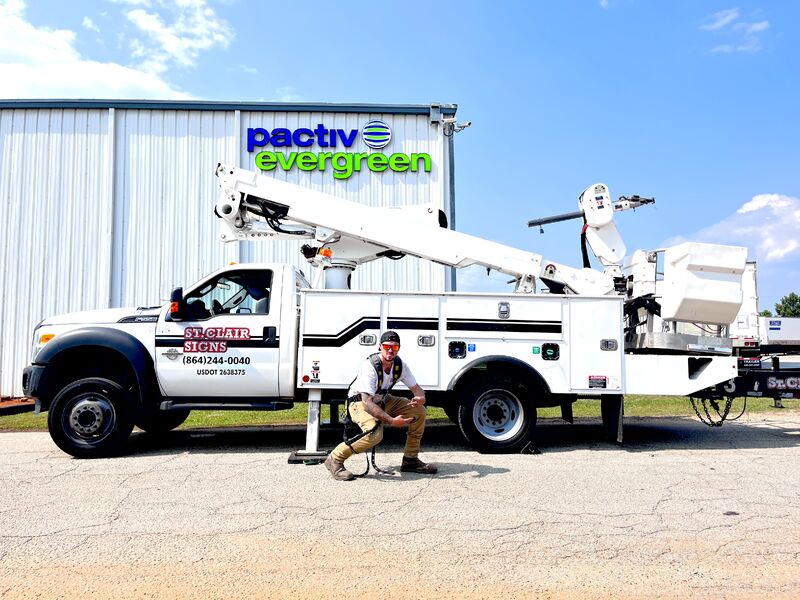 Man posing in front of a cherry picker work truck