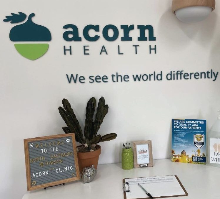 A cubicle desk with Acorn Health written on the wall