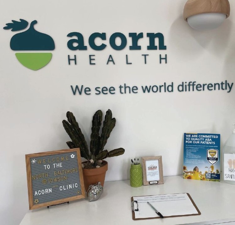 A cubicle desk with Acorn Health written on the wall